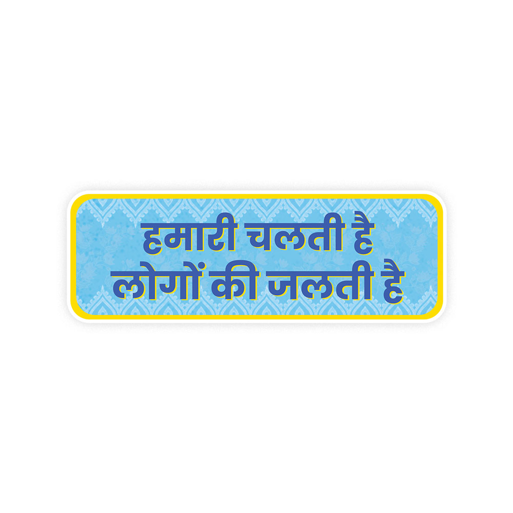 A rectangular sticker with a red background and a white horizontal stripe in the middle. In the center of the white stripe, black Devanagari text reads "घुमक्कड़" which translates to "Wanderer." The red background has faint travel-themed illustrations.