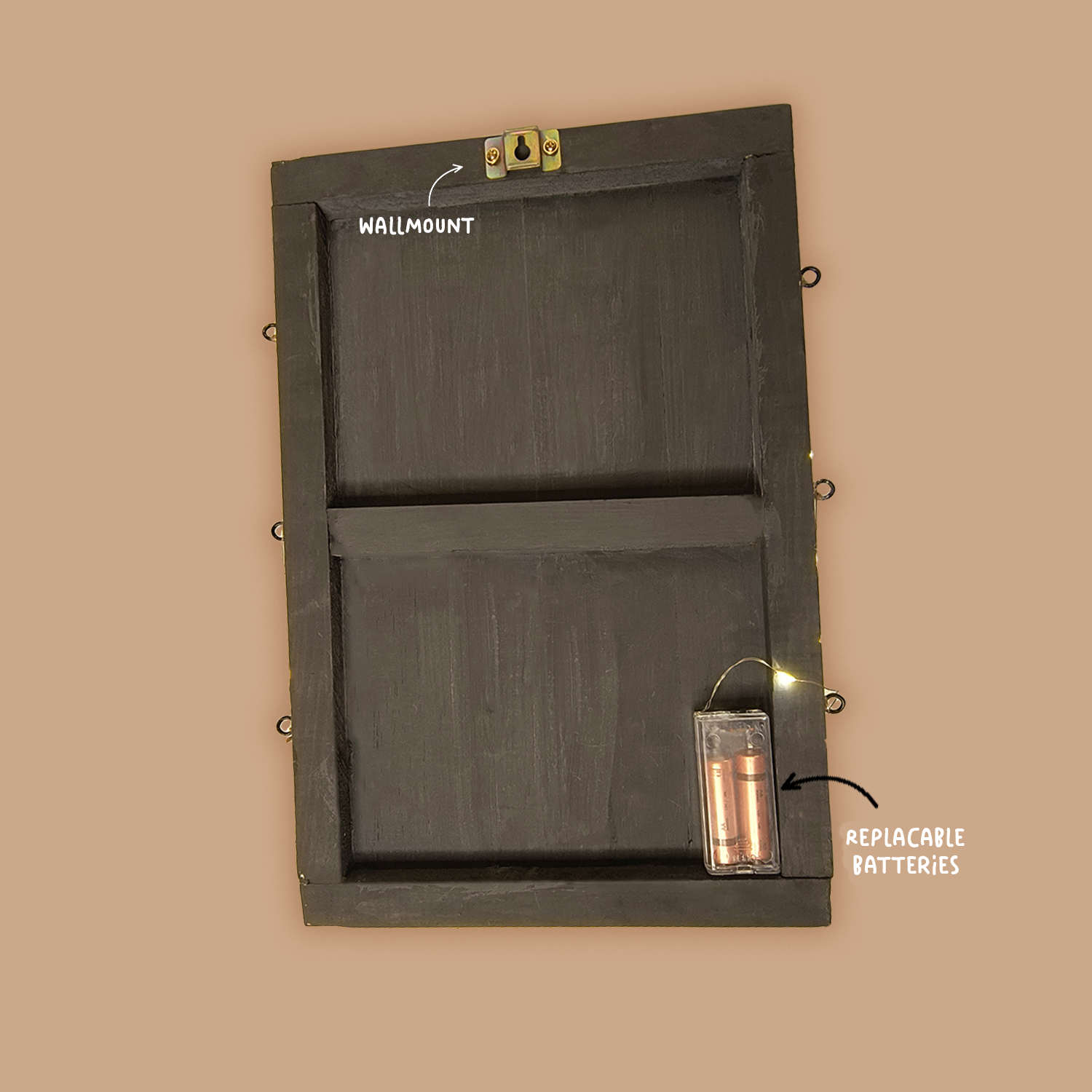 A wooden frame with a wall mount at the top and a compartment labeled "Replaceable Batteries" at the bottom right corner. The frame and labels are against a plain, light brown background.