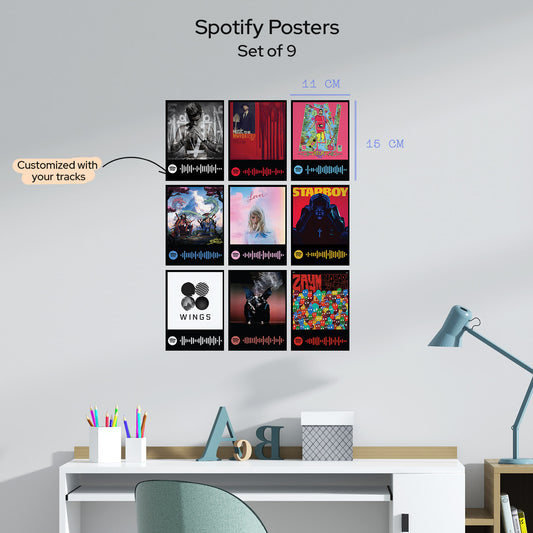 A set of nine personalized Spotify posters featuring various music wall art, displayed on a light gray wall above a desk with a lamp and stationery.